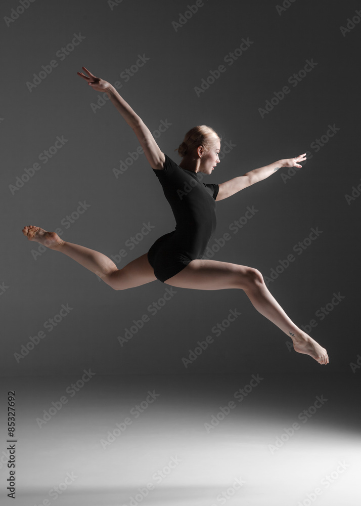 Young beautiful modern style dancer jumping on a studio