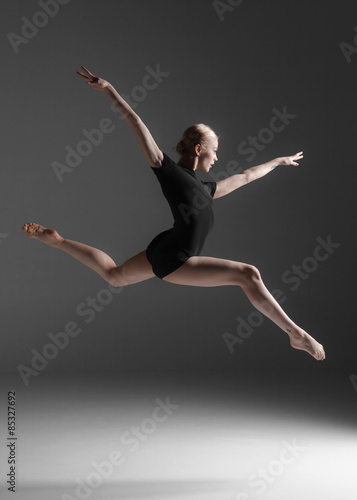 Young beautiful modern style dancer jumping on a studio