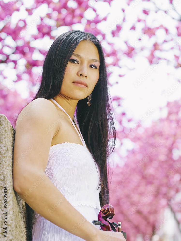 Portrait of young woman with viola in front of blossoming cherry tree Portrait of young woman with viola in front of blossoming cherry tree