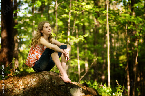 teen girl sitting in a forest daydreaming