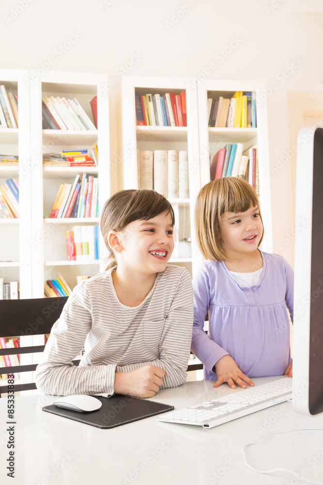 Two sisters spending time together at computer Two sisters spending time together at computer