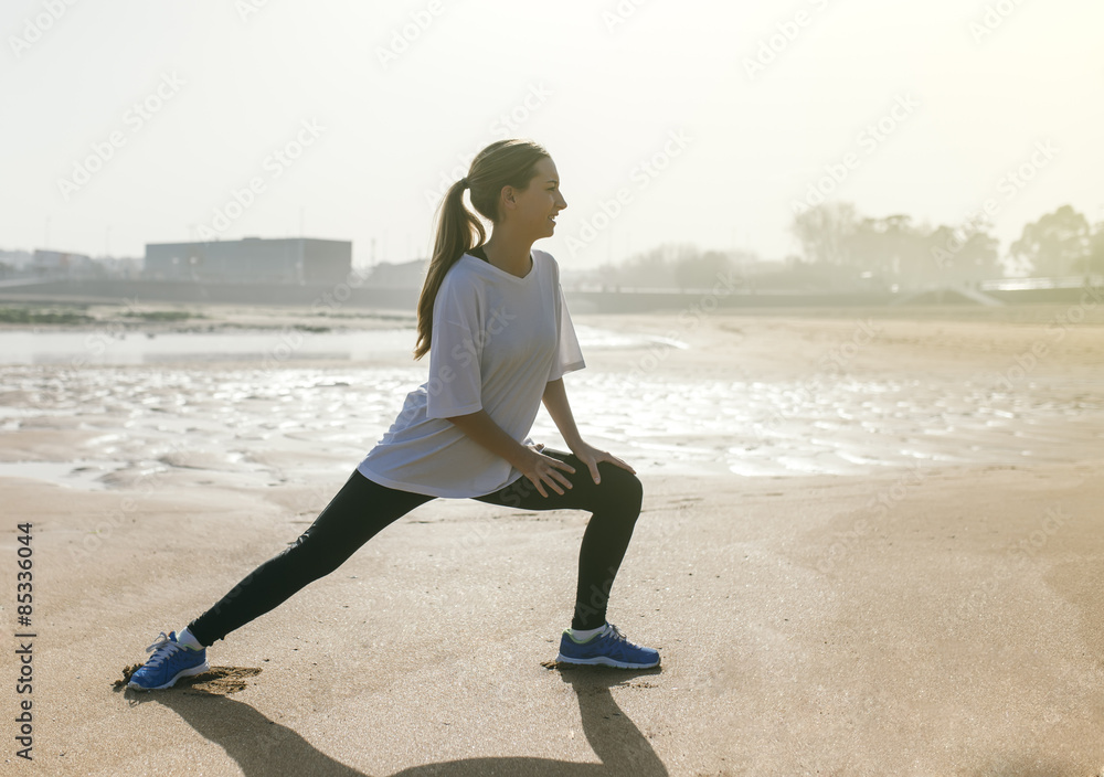 Spain, Gijon, young woman stretching on the beach Spain, Gijon, young woman stretching on the beach