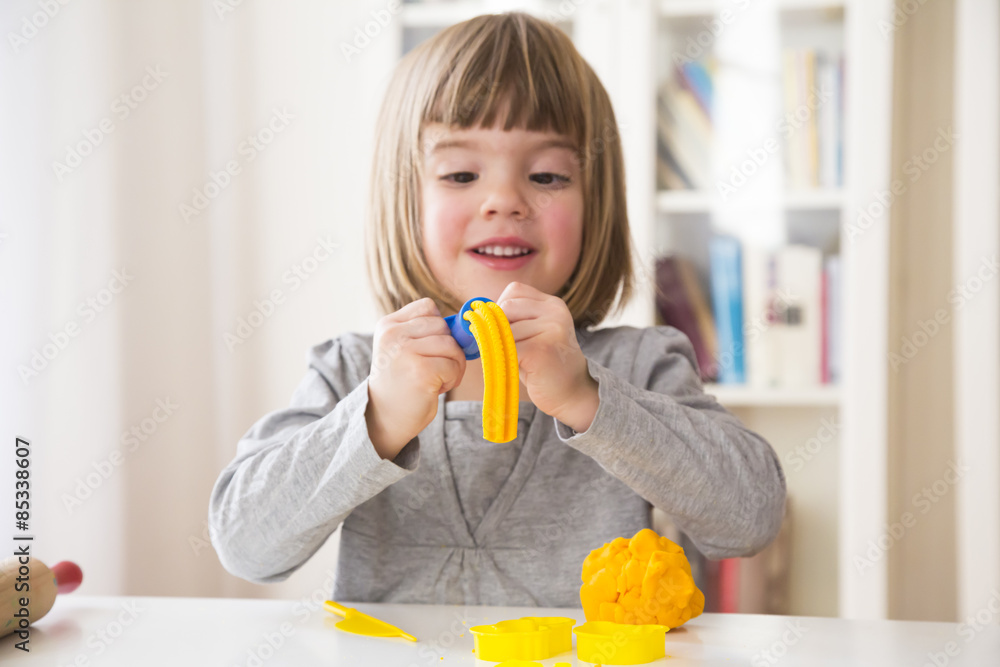 Little girl playing with yellow modeling clay Little girl playing with yellow modeling clay