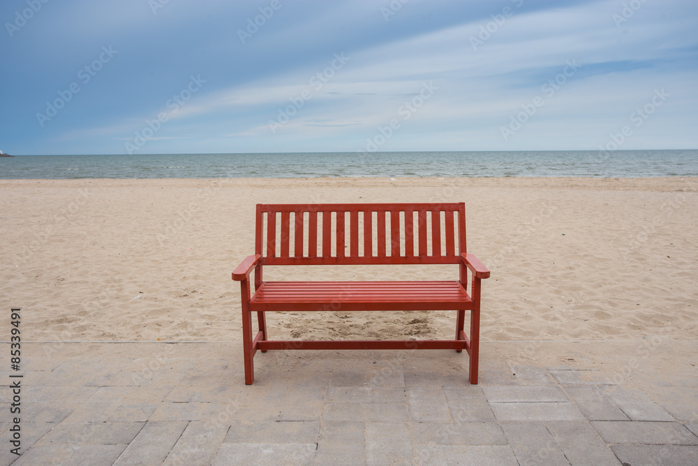 Alone wooden red beach chair sitting on the sand