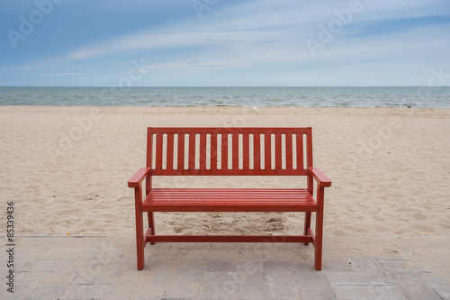Alone wooden red beach chair sitting on the sand with sea