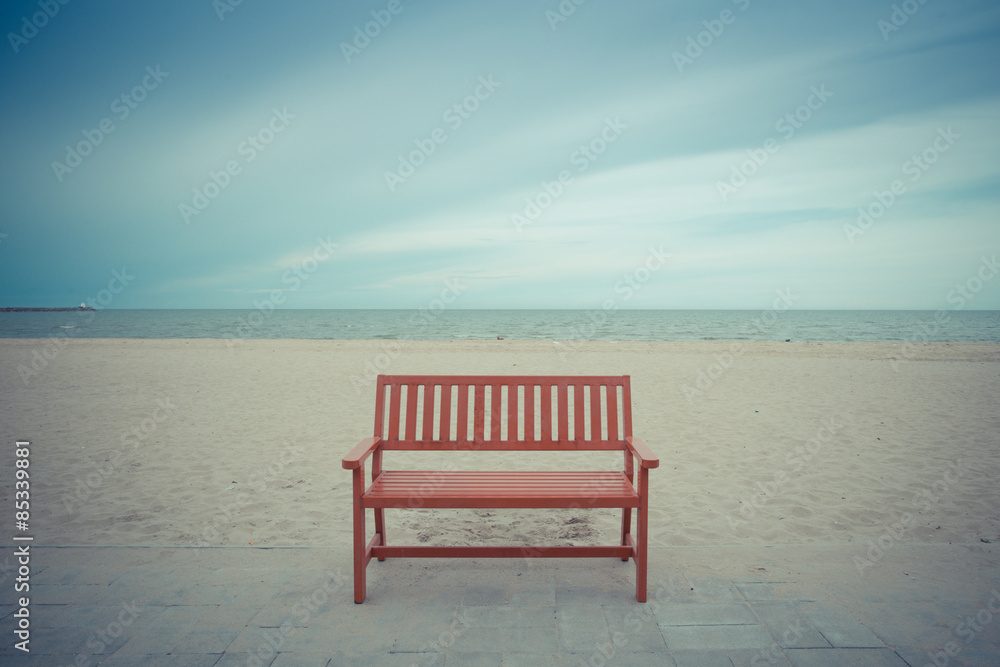 Alone wooden red beach chair sitting on the sand with sea.vintage color