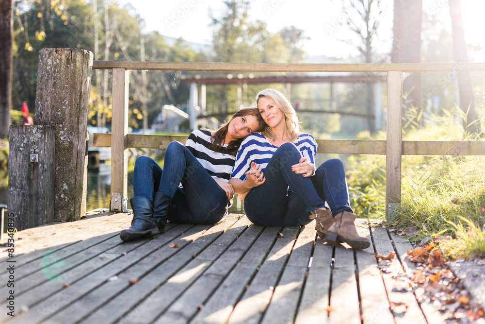 Lesbian couple in love sitting on a jetty Lesbian couple in love sitting on a jetty