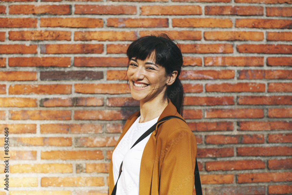 Portrait of laughing businesswoman in front of a brick wall Portrait of laughing businesswoman in front of a brick wall