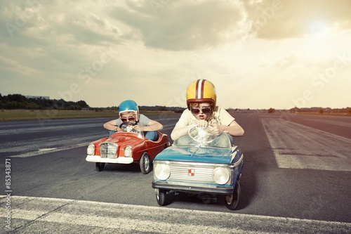 Two boys in pedal cars crossing finishing line on race track photo