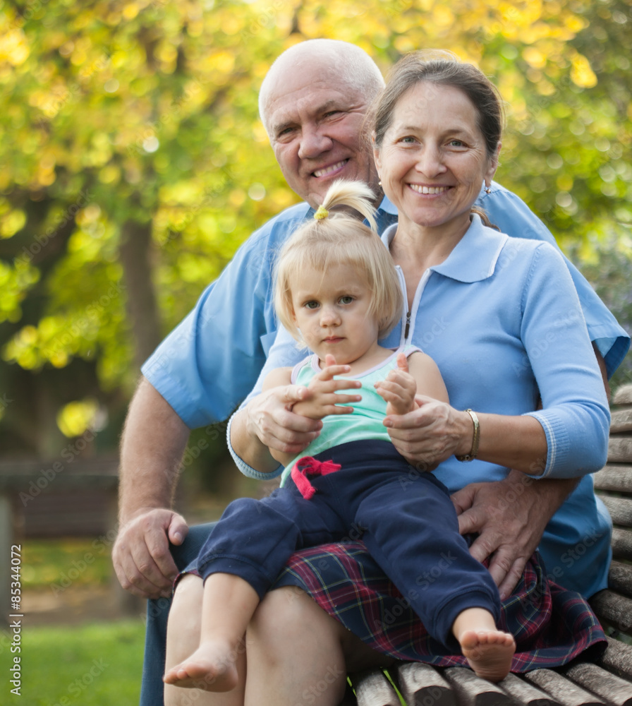 Fototapeta premium mature couple with child sitting on bench