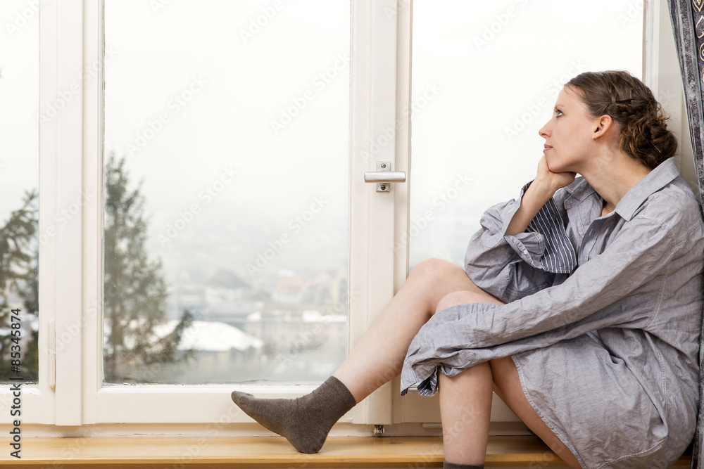 Woman in oversized shirt looking out of window Woman in oversized shirt looking out of window