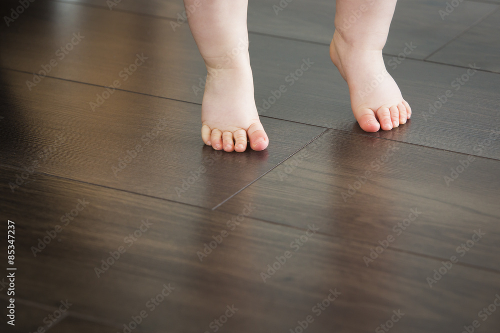 Feet of baby girl on dark floor Feet of baby girl on dark floor