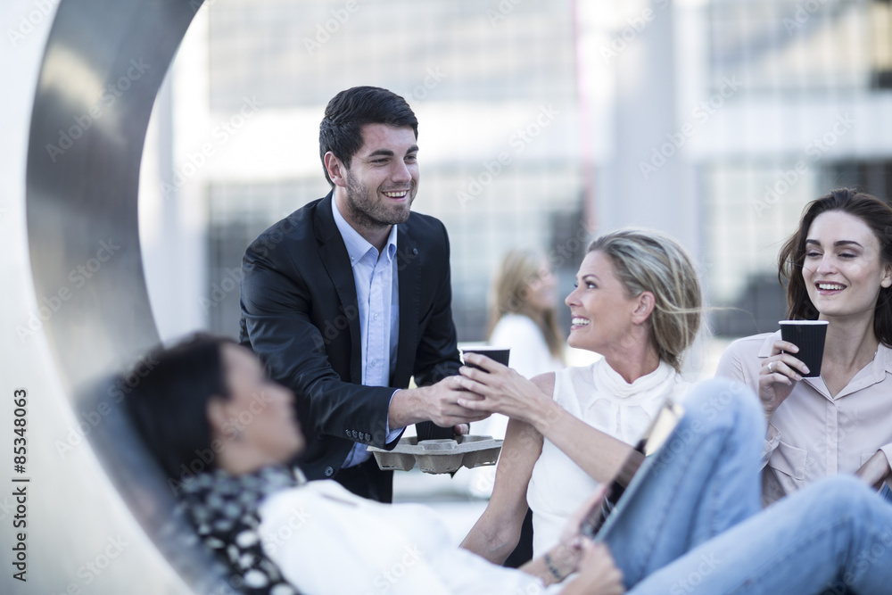 Businessman serving three women coffee to go Businessman serving three women coffee to go