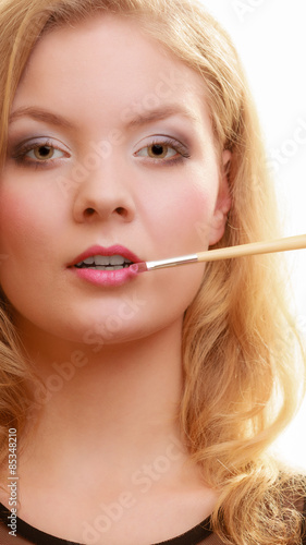 Makeup. Woman applying red lipstick with brush