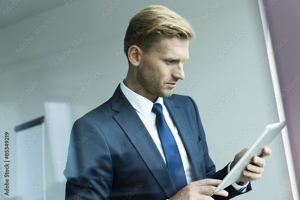 Businessman holding digital tablet, looking down Businessman holding digital tablet, looking down