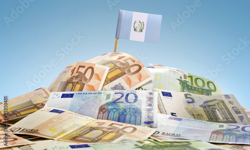 Flag of Guatemala sticking in a pile of various european banknot