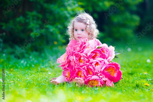 Little girl with peony flowers in the garden © famveldman