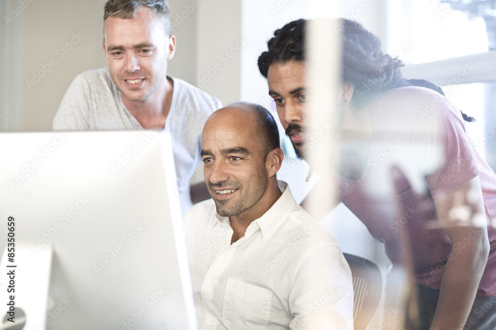 Three colleagues looking at screen in an office Three colleagues looking at screen in an office
