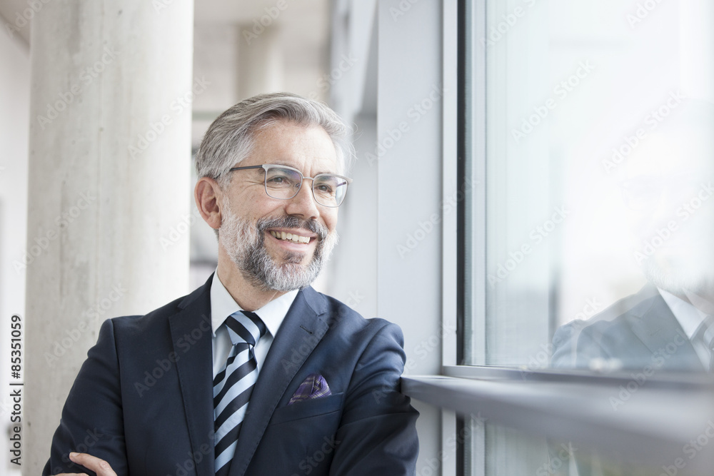 Confident businessman looking out of window Confident businessman looking out of window