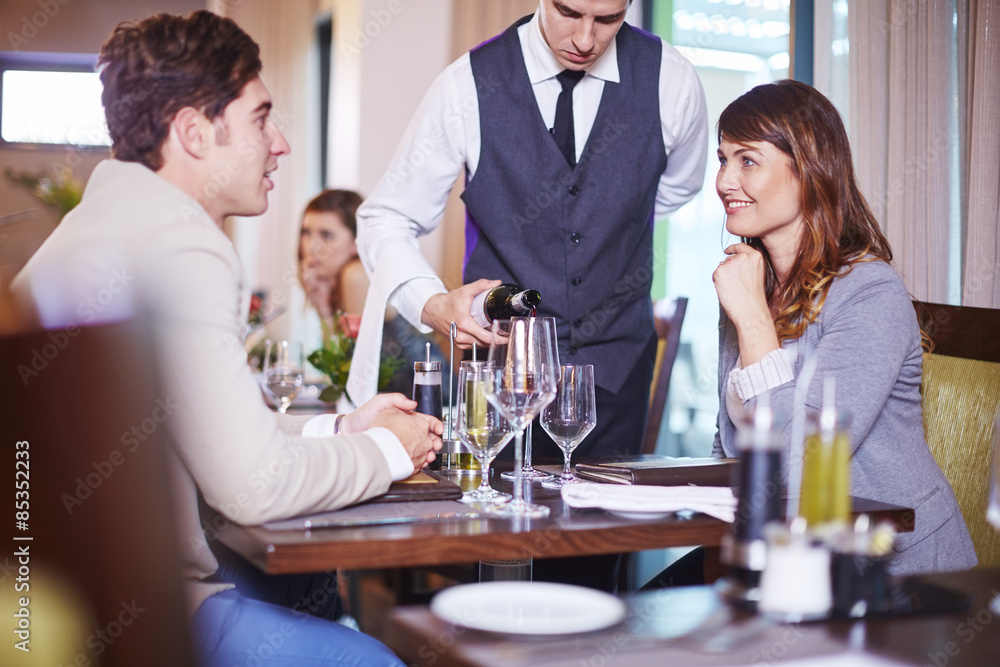 Waiter pouring wine for business associates at hotel restaurant Waiter pouring wine for business associates at hotel restaurant