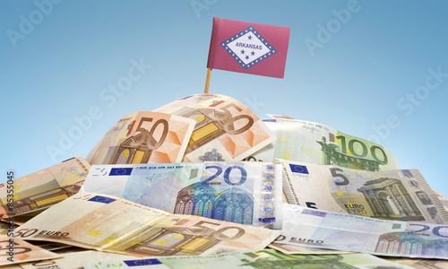 Flag of Arkansas sticking in a pile of various european banknote