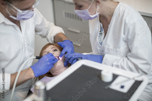 Dentist performing a routine checkup for his patient photo