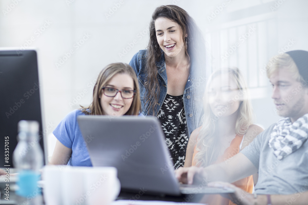 Creative office people having a discussion and working on a laptop Creative office people having a discussion and working on a laptop
