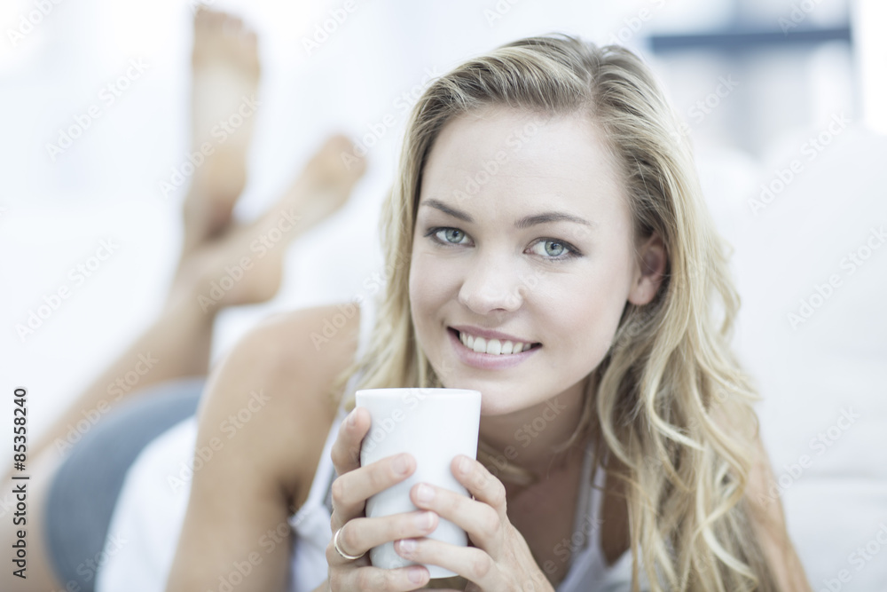 Portrait of blond woman lying on a couch with cup of coffee Portrait of blond woman lying on a couch with cup of coffee