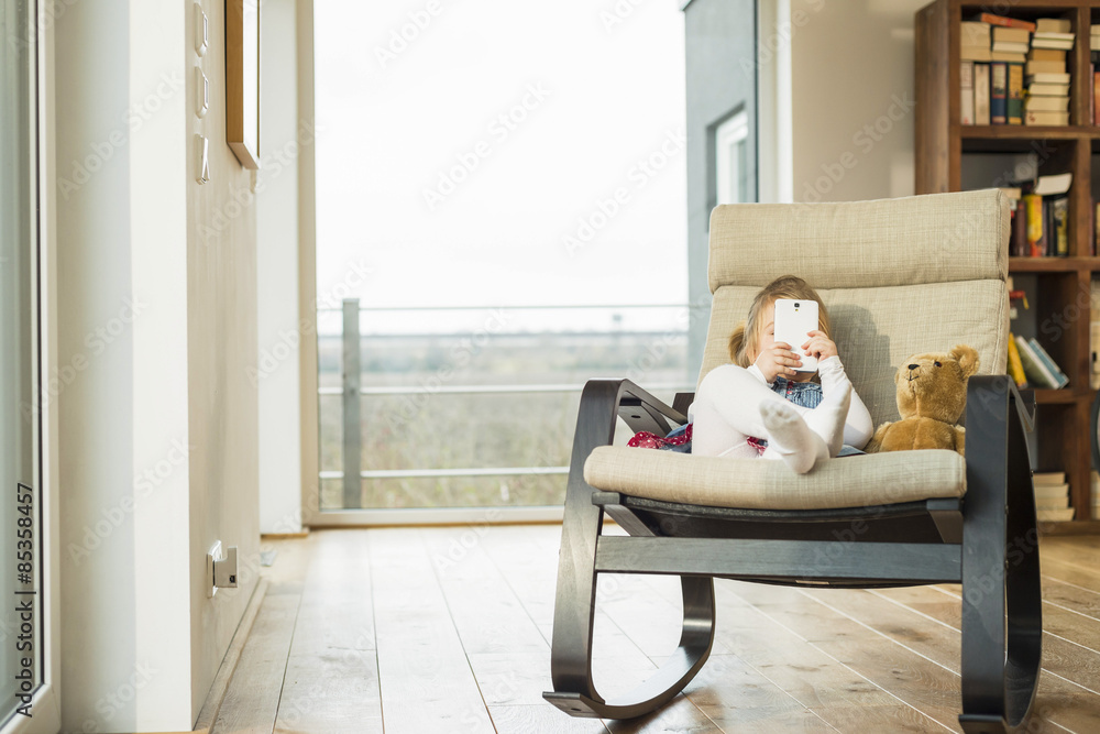 Girl sitting in rocking chair using smartphone Girl sitting in rocking chair using smartphone