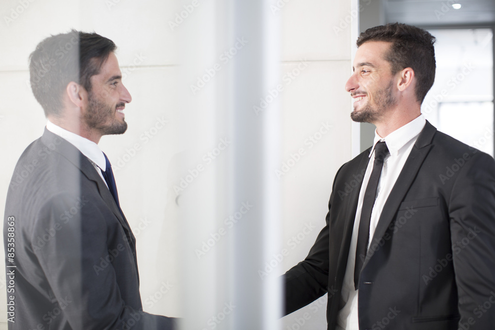 Two businessmen shaking hands in office Two businessmen shaking hands in office
