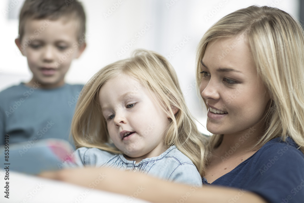 Mother and little daughter sitting on a couch reading a book Mother and little daughter sitting on a couch reading a book