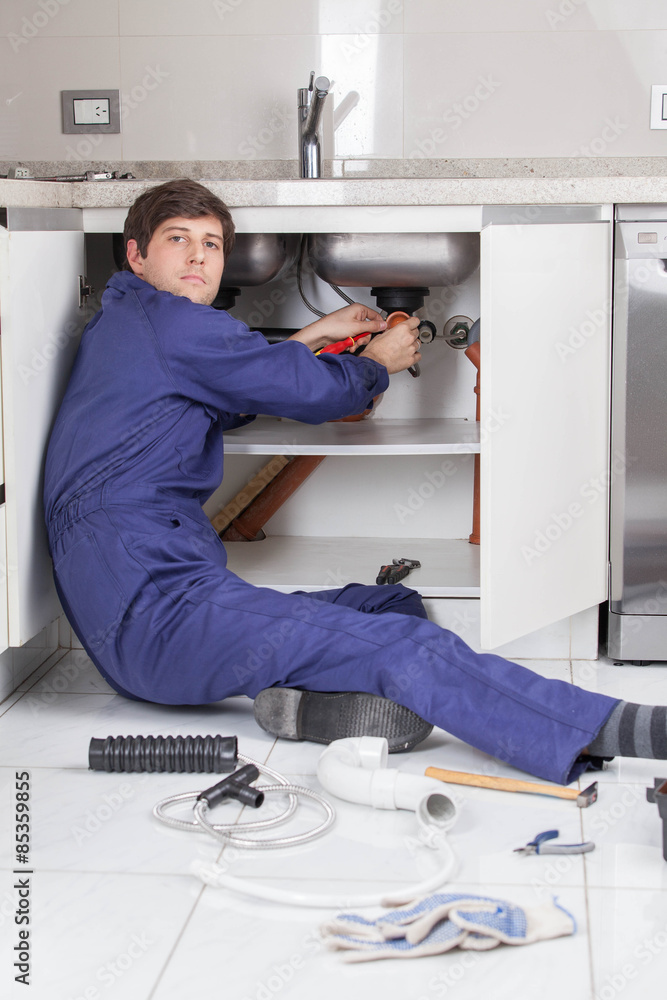 Plumber sitting on the floor repair a pipe Plumber sitting on the floor repair a pipe