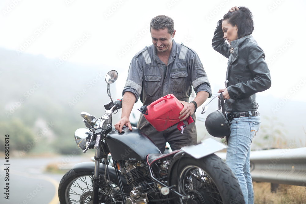 Motorcycle technician helping stranded biker with broken bike Motorcycle technician helping stranded biker with broken bike