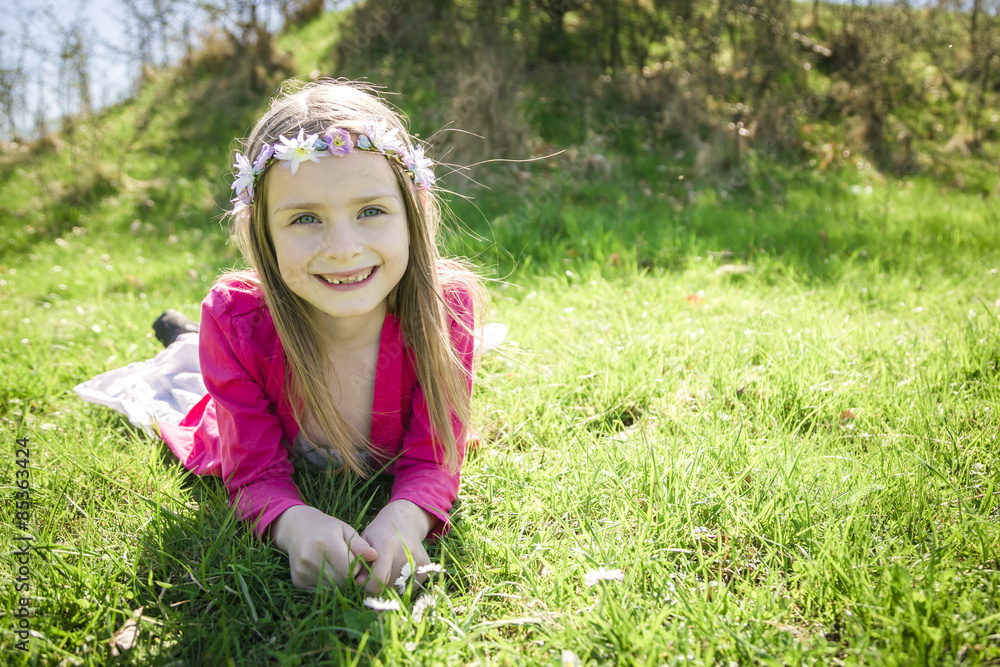 Portrait of smiling girl wearing flowers lying on a meadow Portrait of smiling girl wearing flowers lying on a meadow