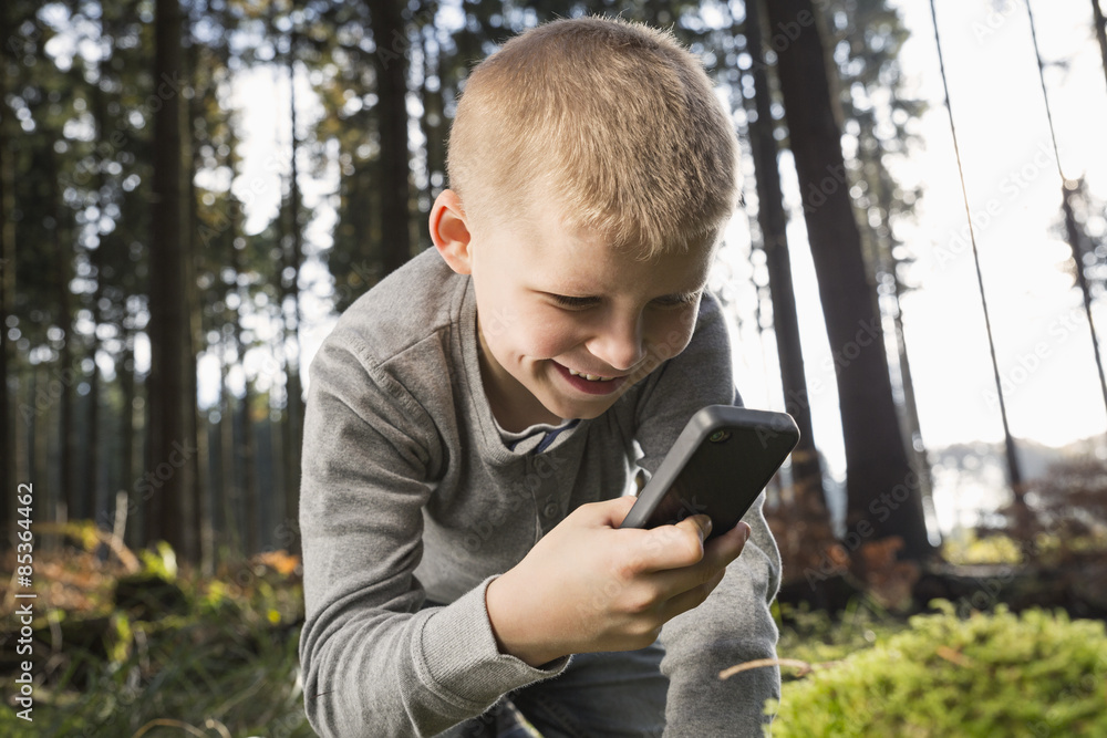 Germany, smiling little boy photographing nature in a forest Germany, smiling little boy photographing nature in a forest