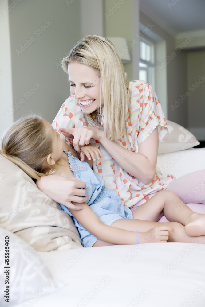 Mother and daughter sitting on sofa, playing Mother and daughter sitting on sofa, playing