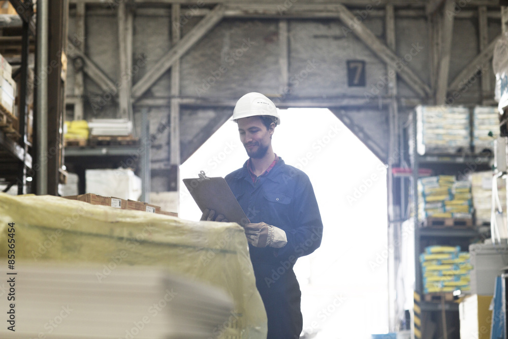 Warehouseman in storehouse holding clipboard Warehouseman in storehouse holding clipboard