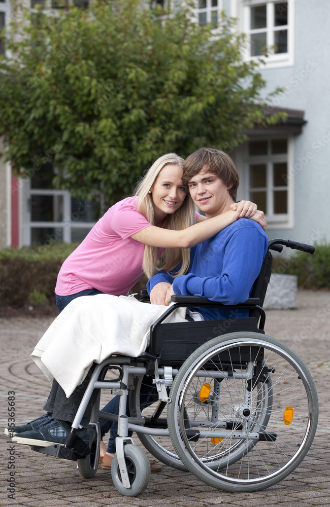 Young woman embracing her boyfriend sitting in wheelchair Young woman embracing her boyfriend sitting in wheelchair