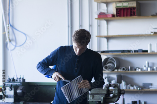 Technician in workshop working on piece of metal photo