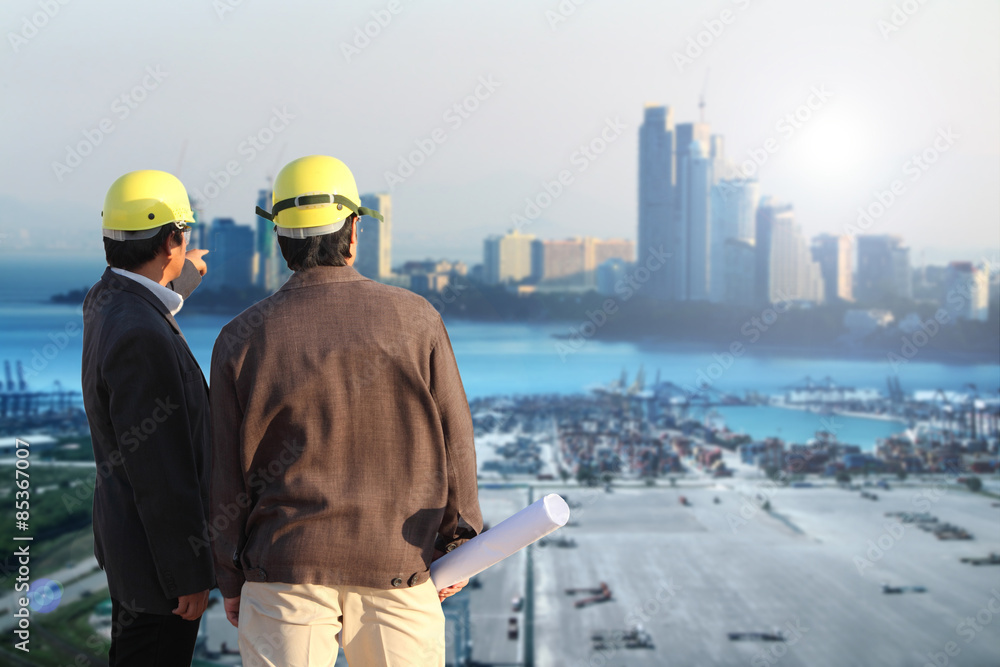 two engineer on site with cranes at the container port terminal with big city background two engineer on site with cranes at the container port terminal with big city background