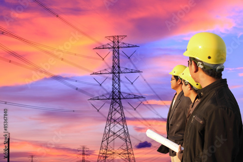 three engineers standing at electricity station, discussing plan photo