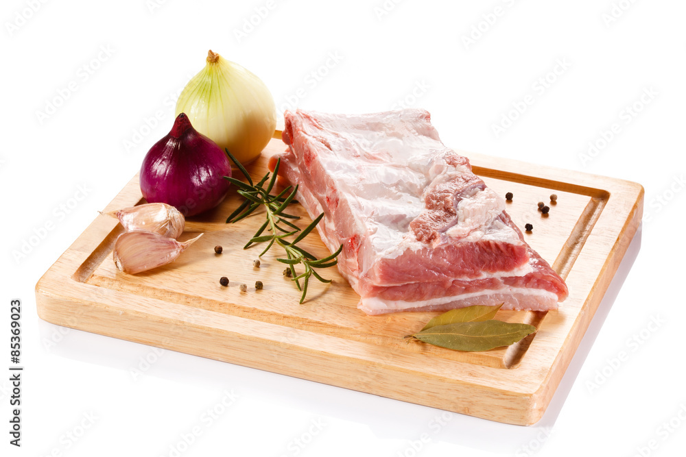 Raw pork ribs on cutting board and vegetables Raw pork ribs on cutting board and vegetables