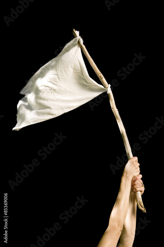 Hands holding white rag tied to a stick against a black background photo