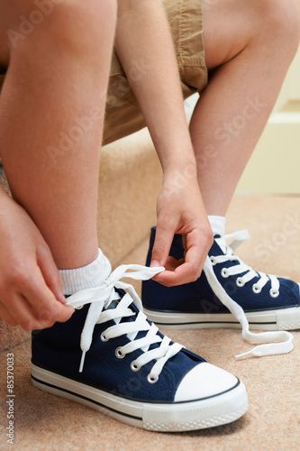 Boy Sitting On Stairs Tying Shoelaces
