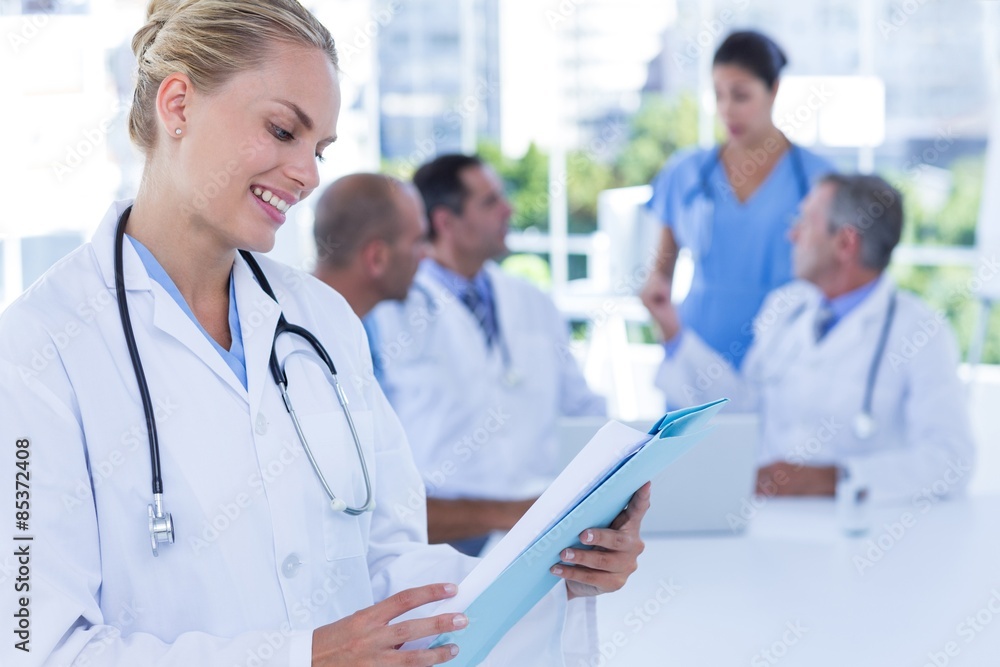 Smiling female doctor looking at clipboard Smiling female doctor looking at clipboard