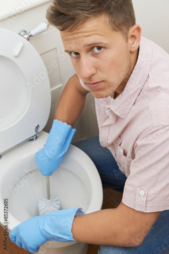 Portrait Of Unhappy Man Cleaning Toilet