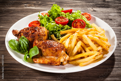 Grilled chicken legs with chips and vegetables 