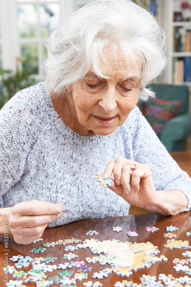 Senior Woman Relaxing With Jigsaw Puzzle At Home Senior Woman Relaxing With Jigsaw Puzzle At Home