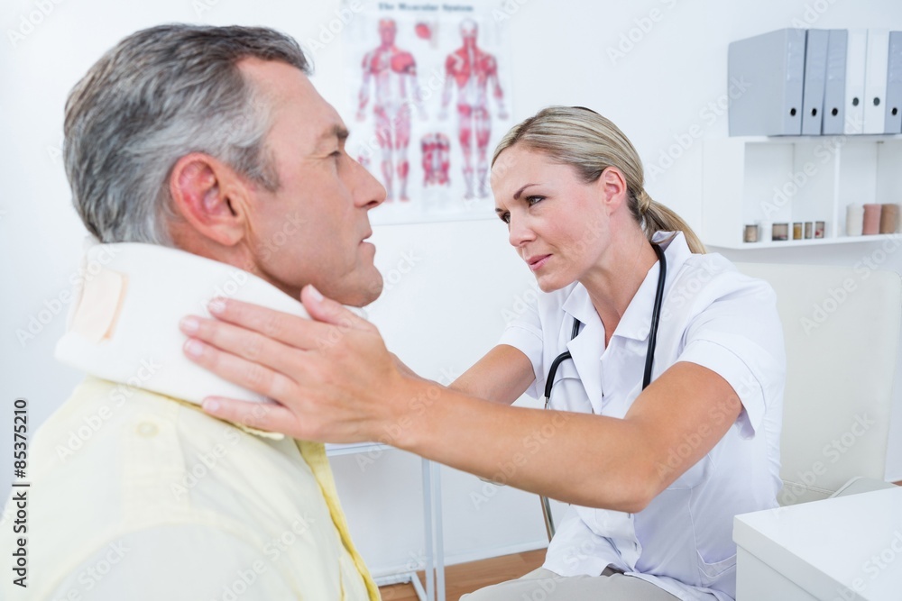 Obraz premium Doctor examining patient wearing neck brace