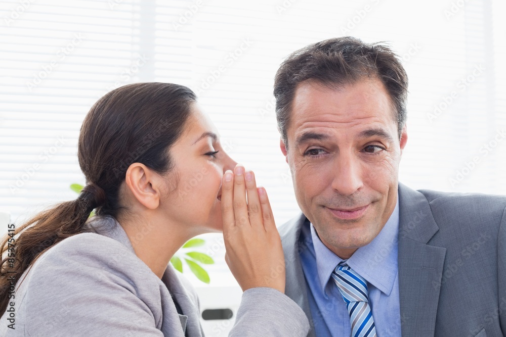 Businesswoman whispering something to her colleague Businesswoman whispering something to her colleague
